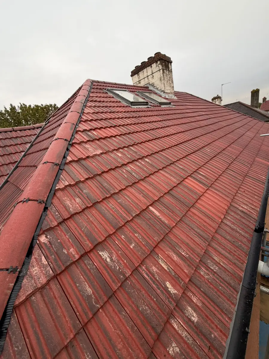 Finished re-roof in East Ham with red interlocking tiles, a dry hip, a roof window and the chimney stack