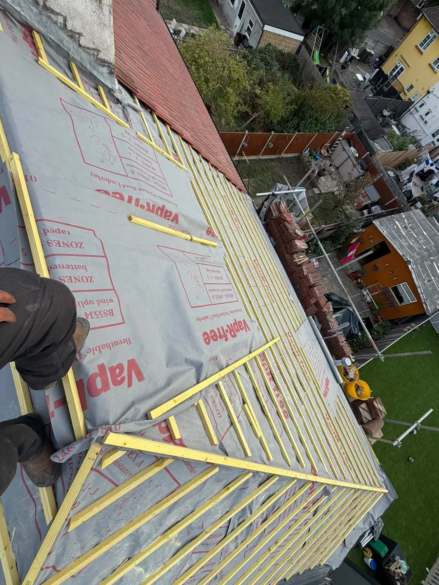 New breathable membrane and battens on the stripped roof in East Ham with the tiles stacked on the scaffold