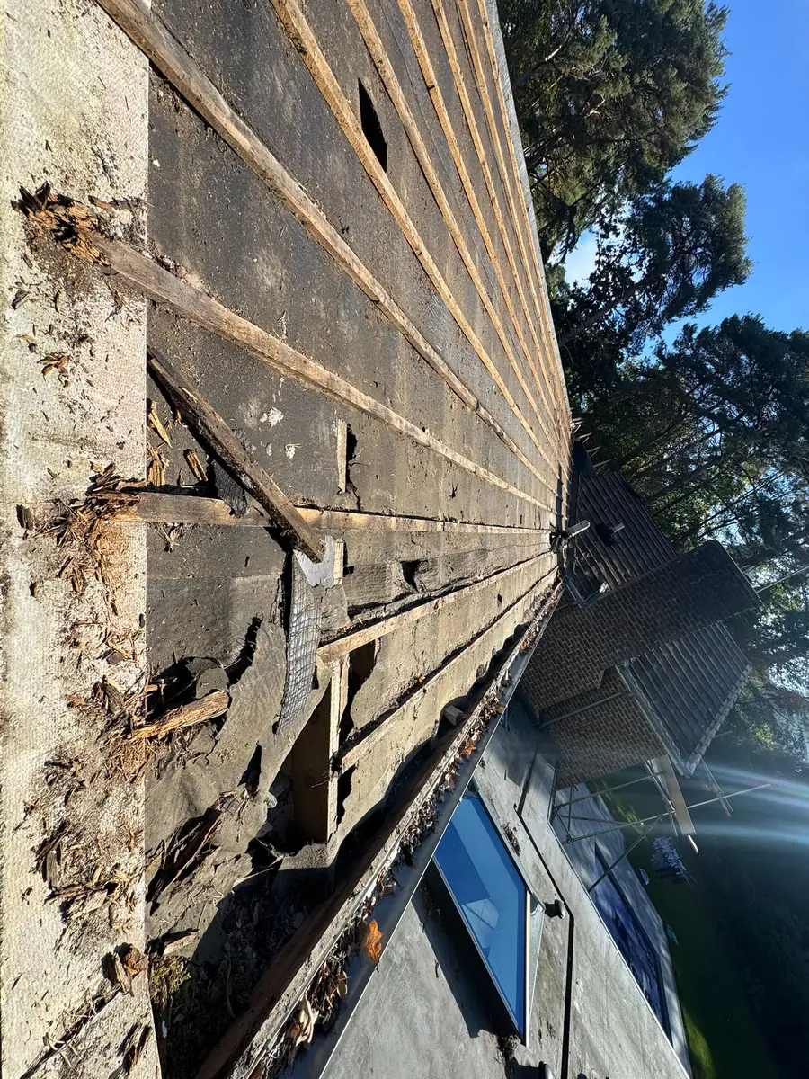 Old roof in Fleet stripped back, showing tired battens and old underlay breaking up at the eaves