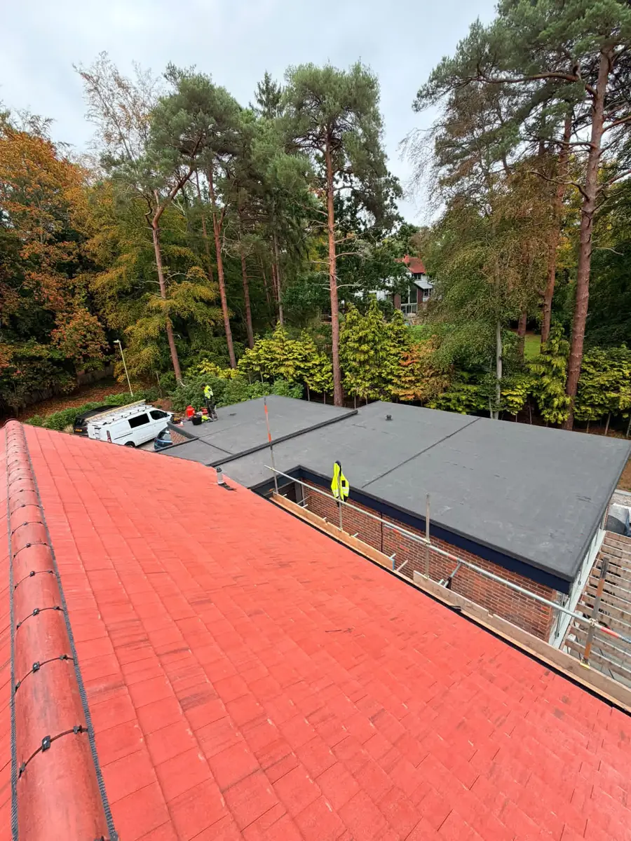View along the new dry ridge over the finished flat roofs and black edge trims in Fleet