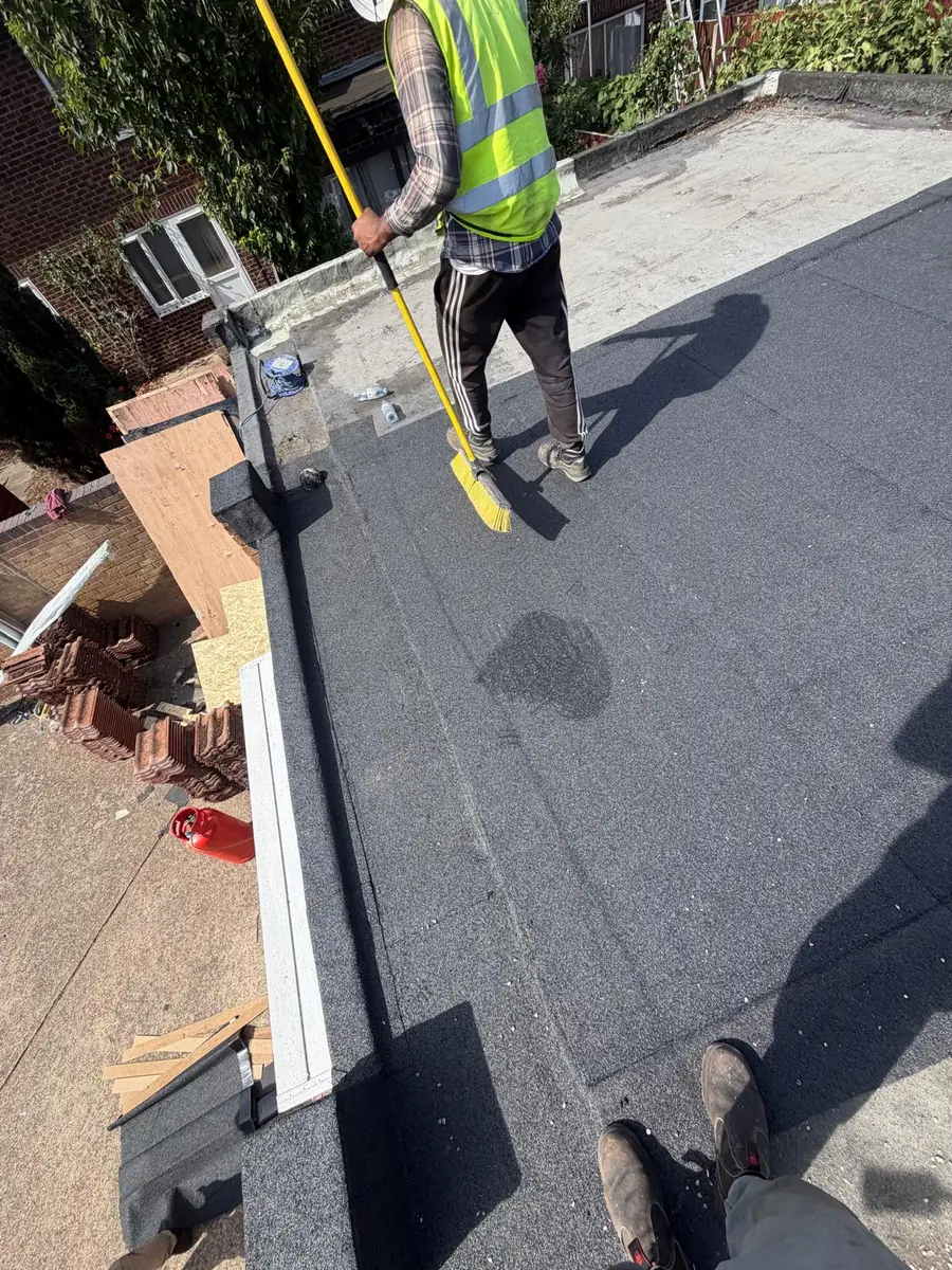 Finished grey mineral felt flat roof in Hampton being swept down by the team