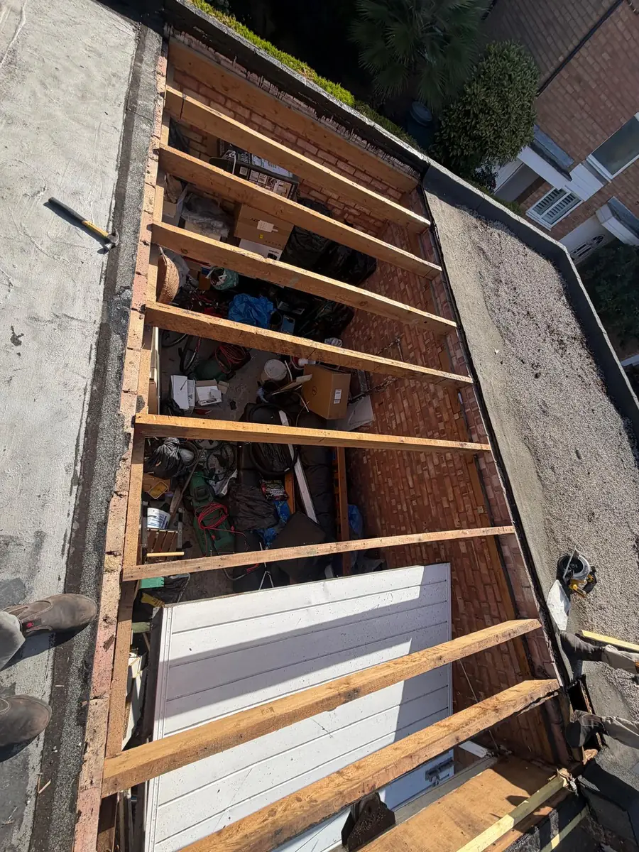 Hampton garage flat roof stripped back to the bare joists before re-decking