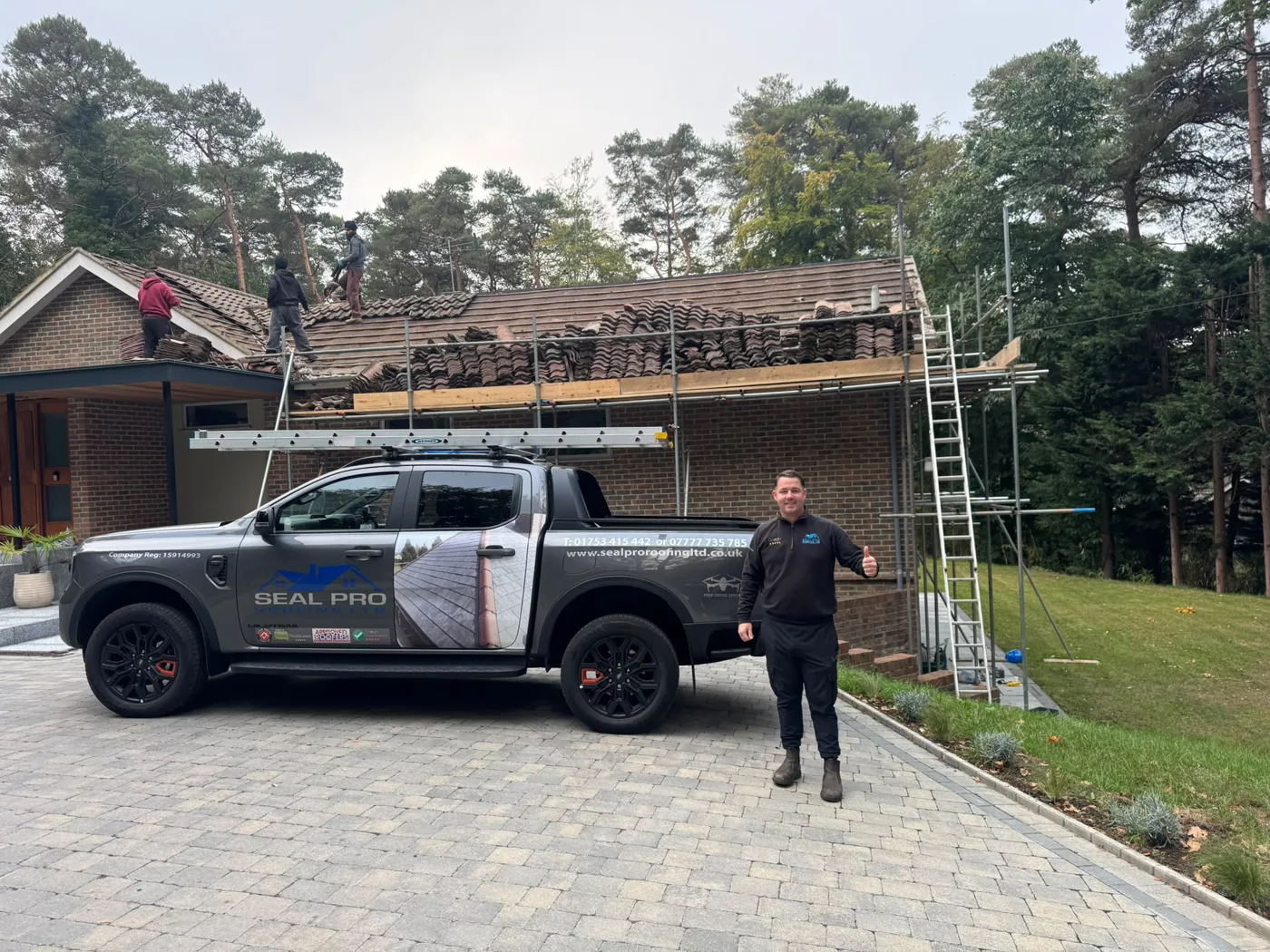 Seal Pro Roofing re-roofing a house, scaffold up and old tiles stripped, with owner Cornelius beside the company truck